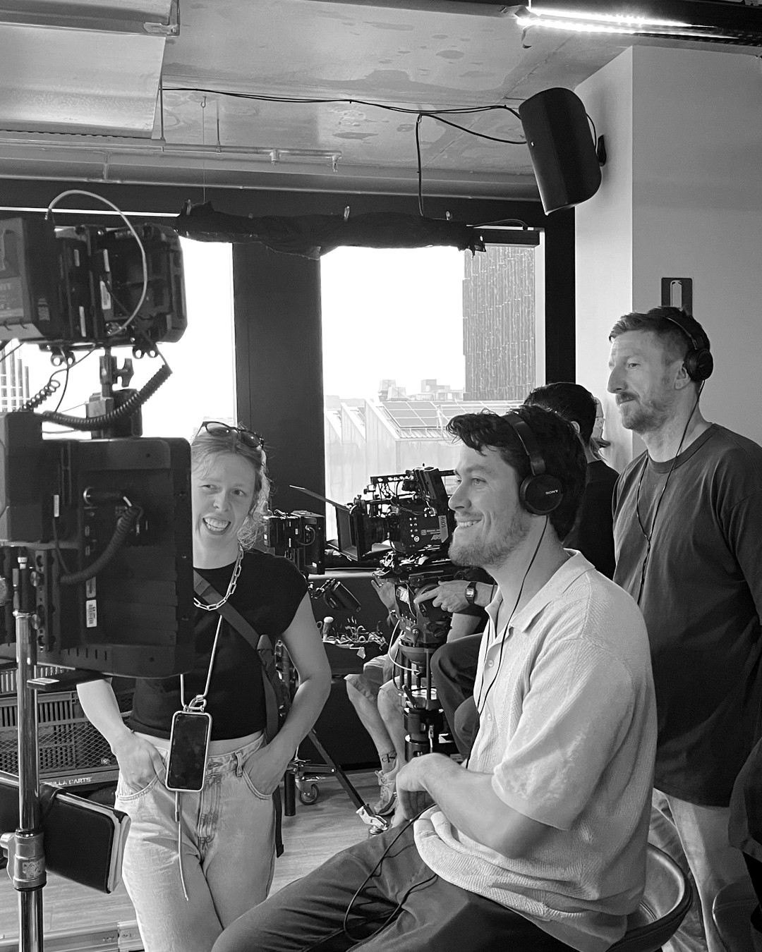 Cameron March on set in headphones, laughing at the monitor with his crew